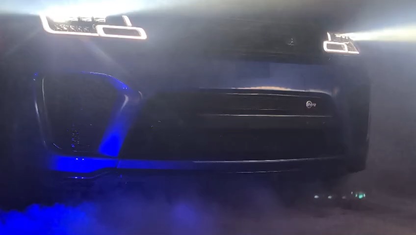 A Range Rover SVR nose-on in smoke and workshop light beams