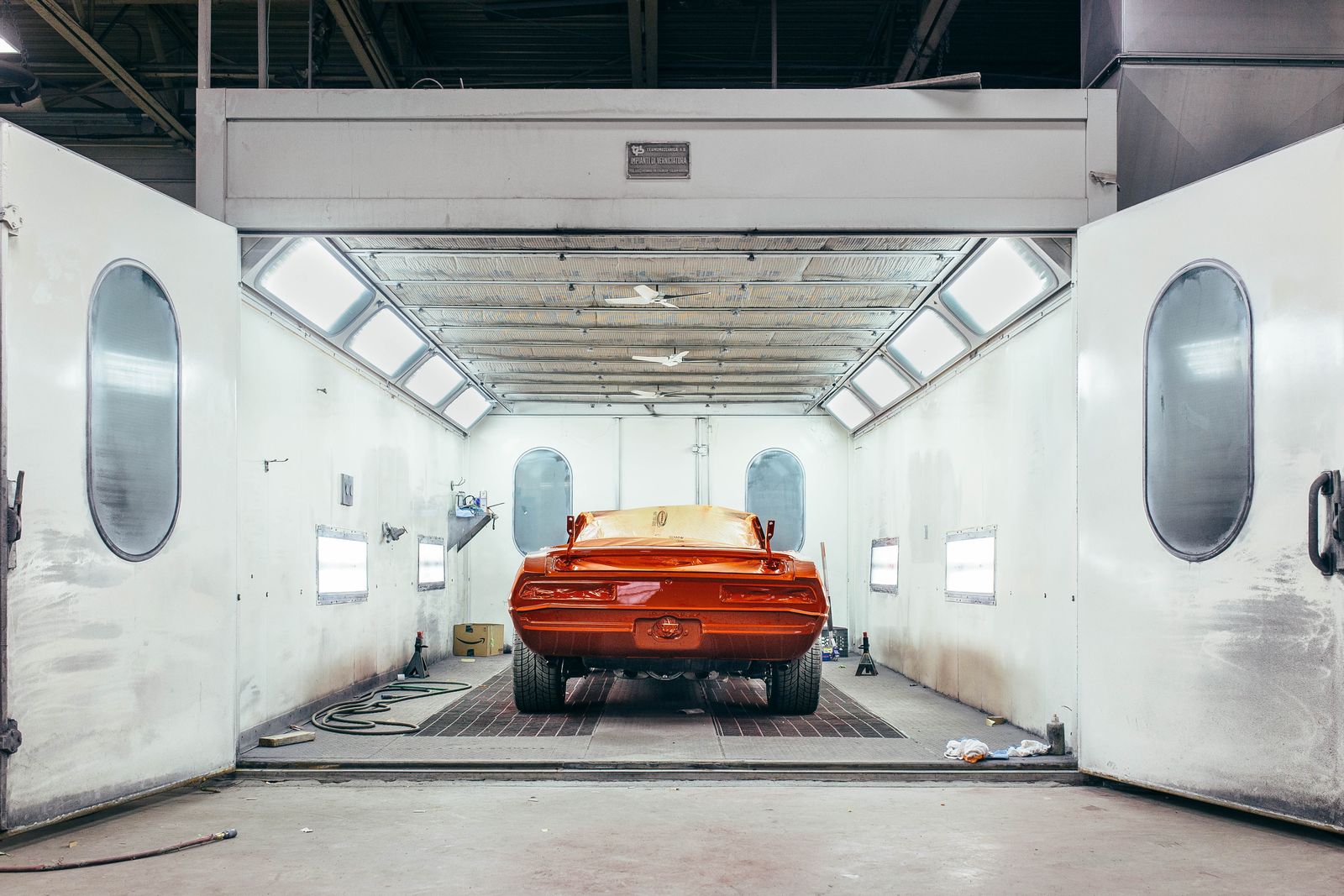 A freshly painted orange muscle car in the spray booth