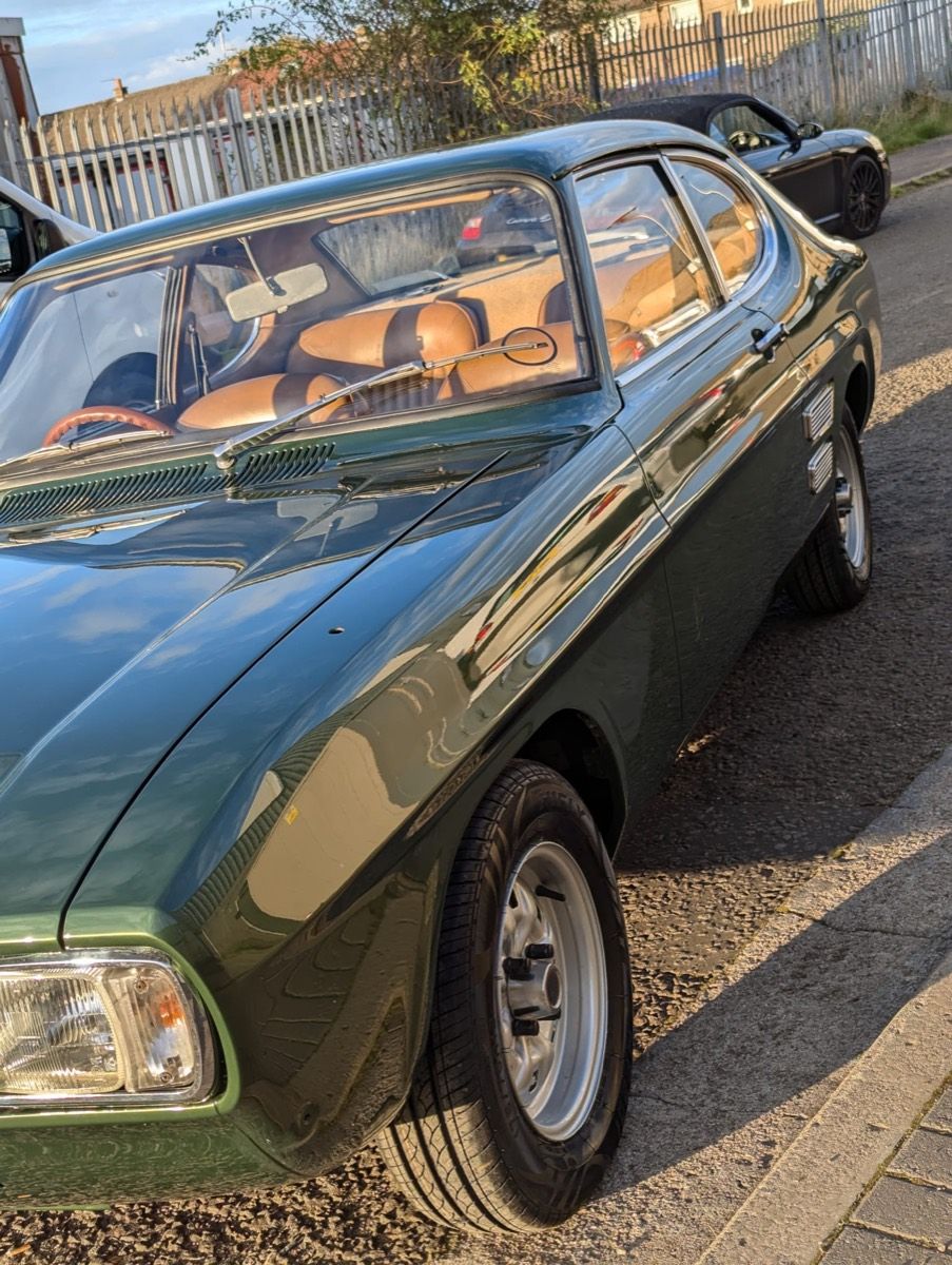 A restored Ford Capri in deep green with a tan interior, front three-quarter view