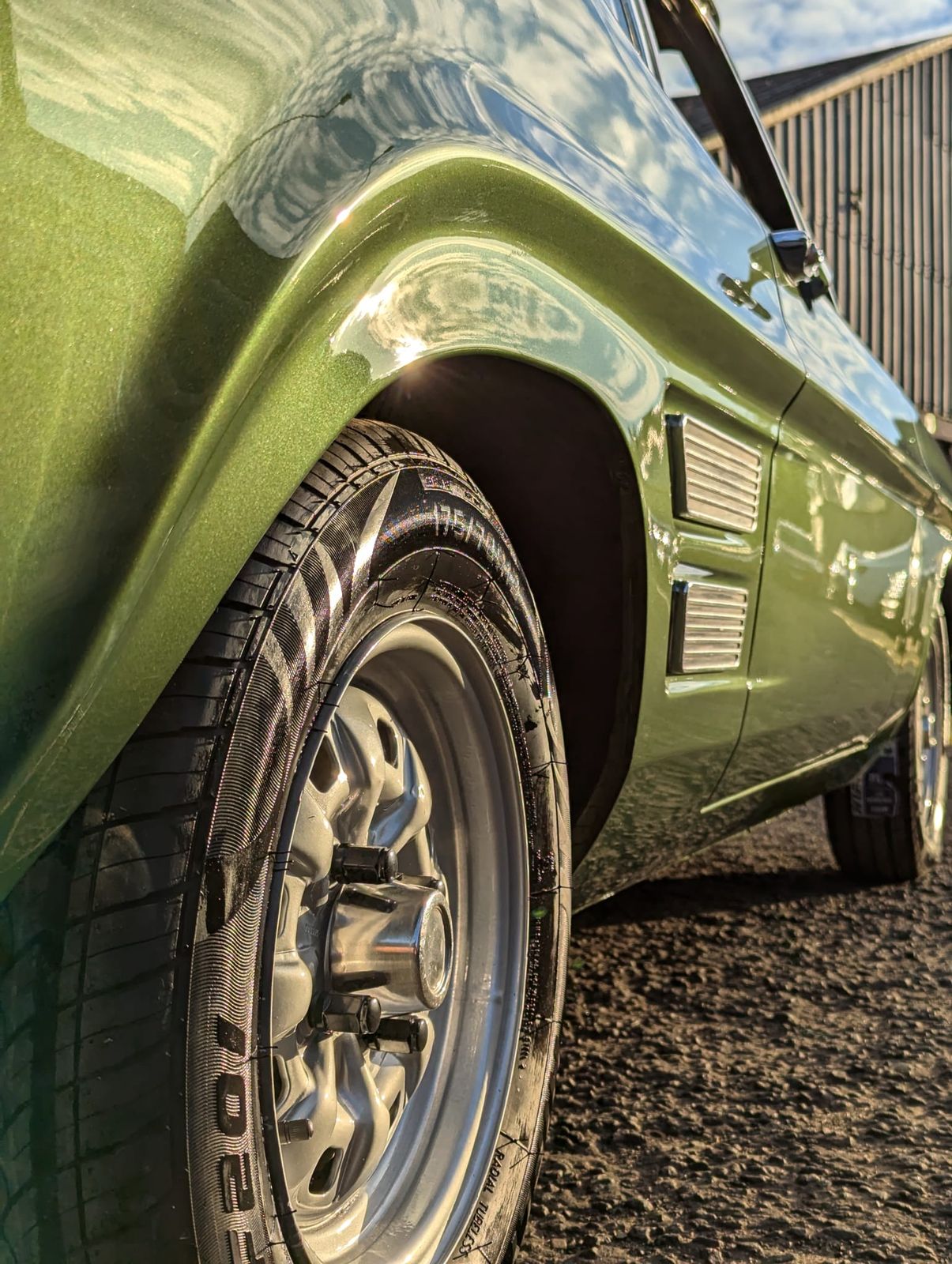 The rear wing of a classic Ford Capri in deep green, refinished to a mirror gloss