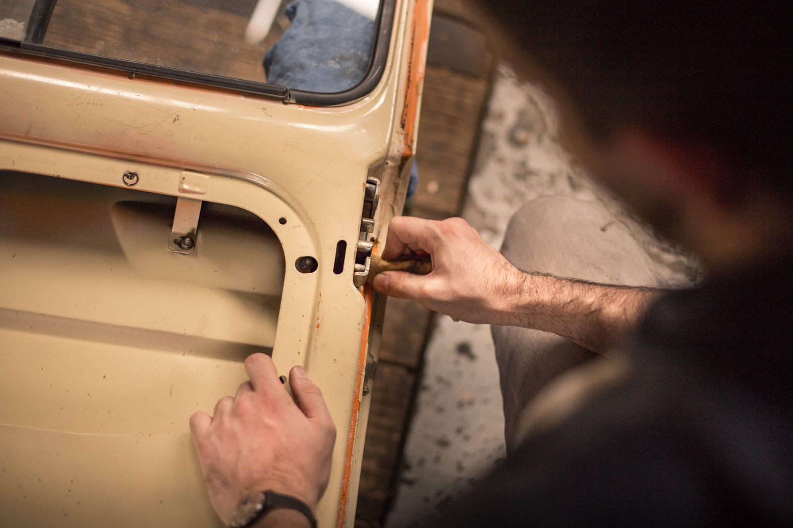 Hands working the door of a classic car by hand