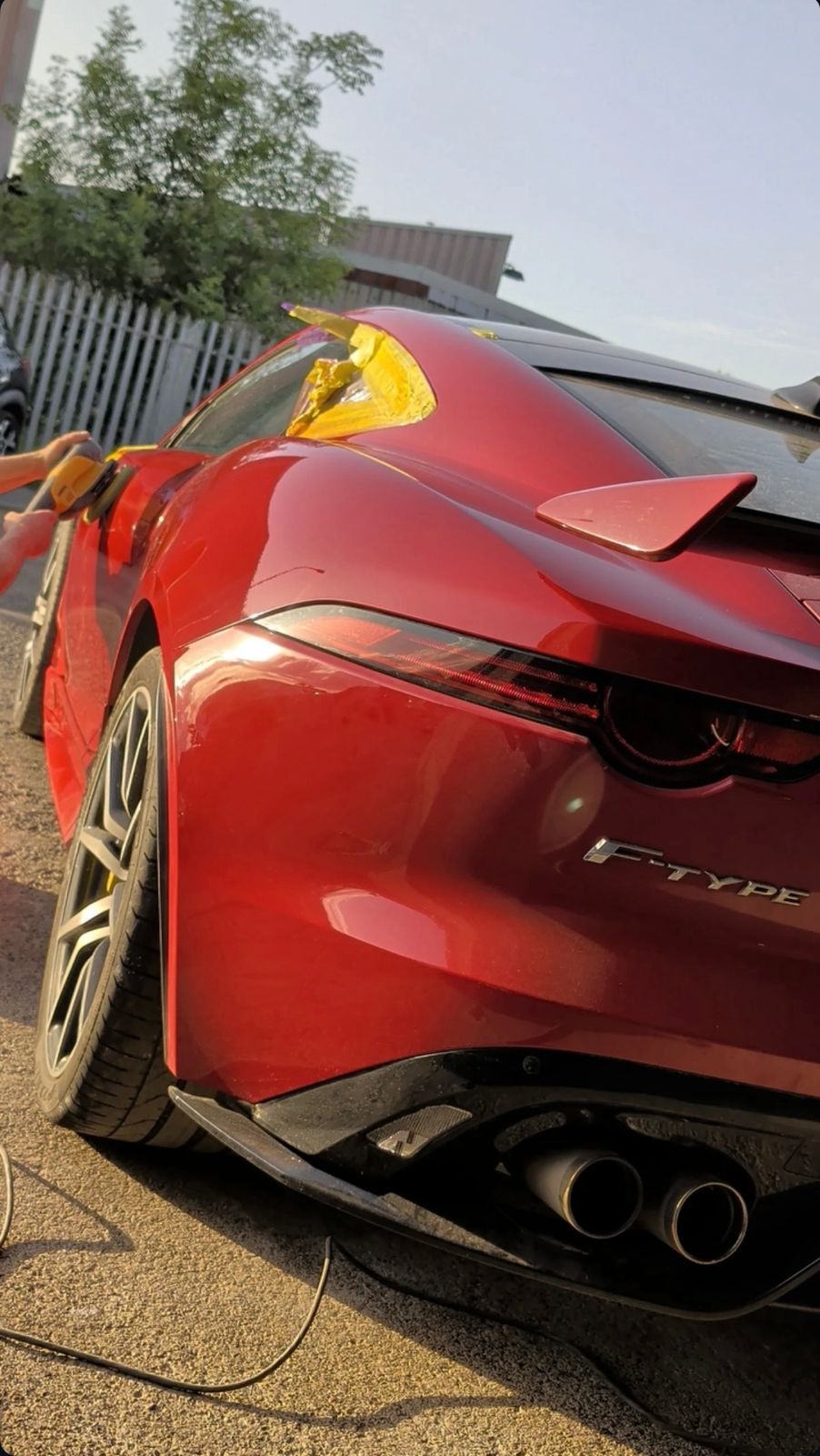 The rear of a red Jaguar F-Type mid detail at the workshop