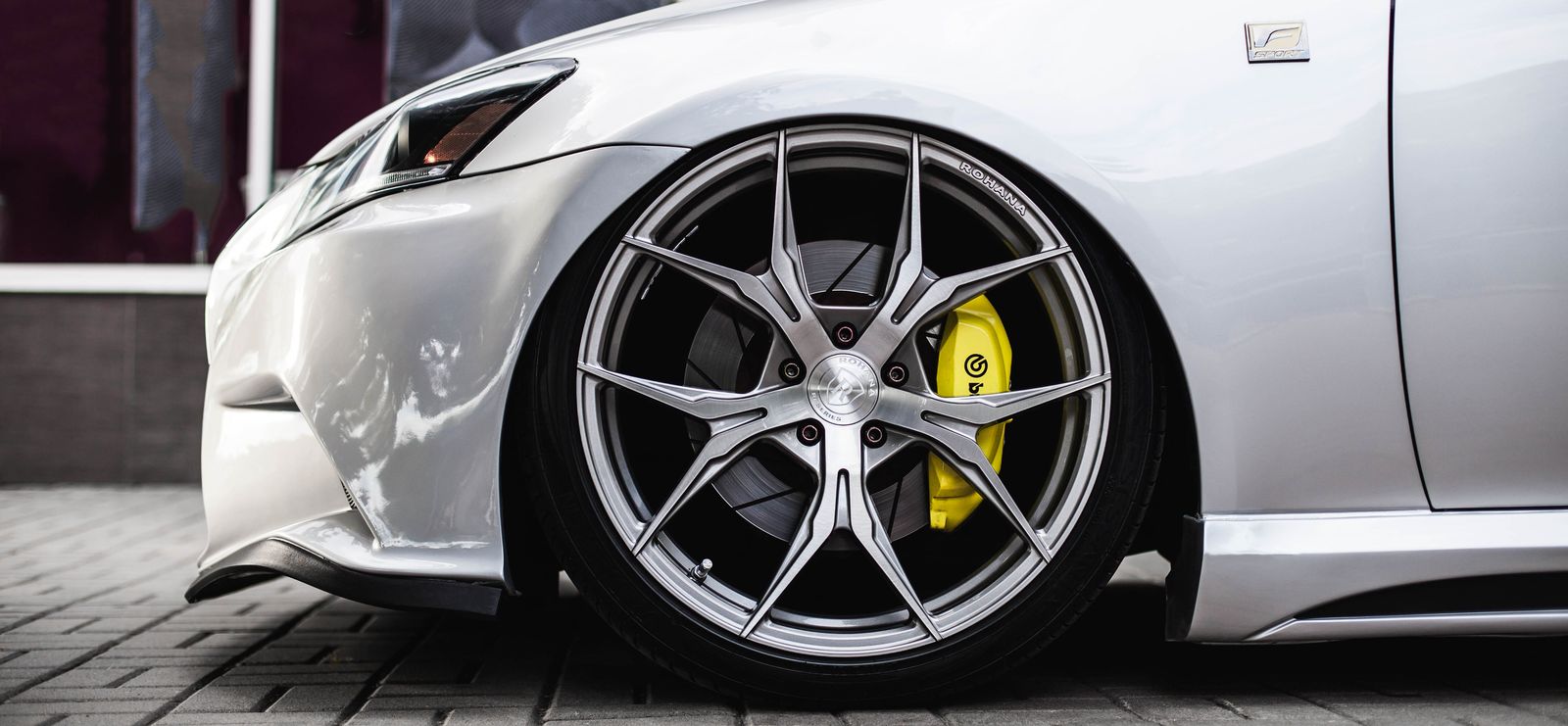 A lowered silver Lexus on aftermarket alloys with a black front splitter