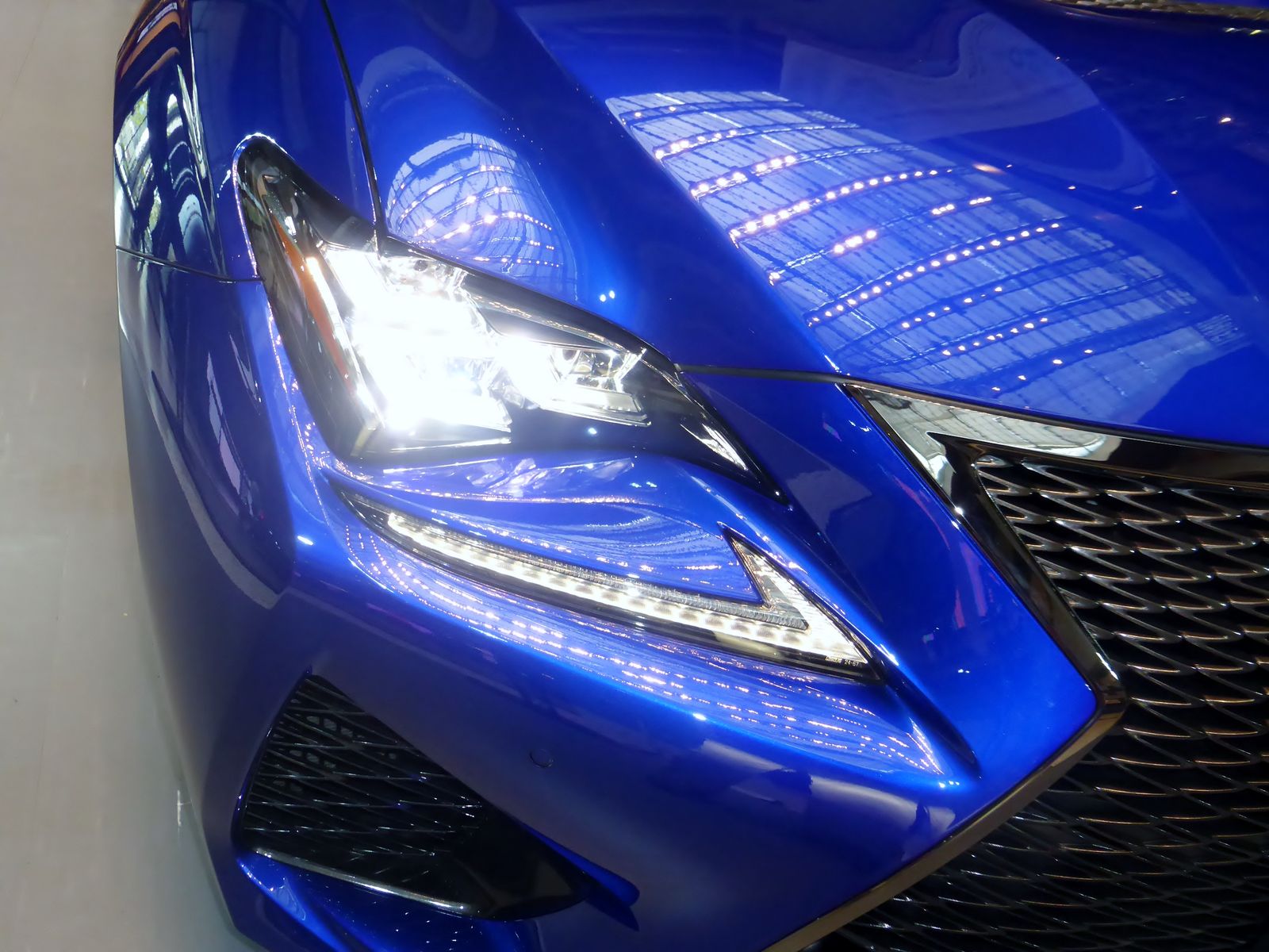 The headlamp and front wing of a blue Lexus, close up