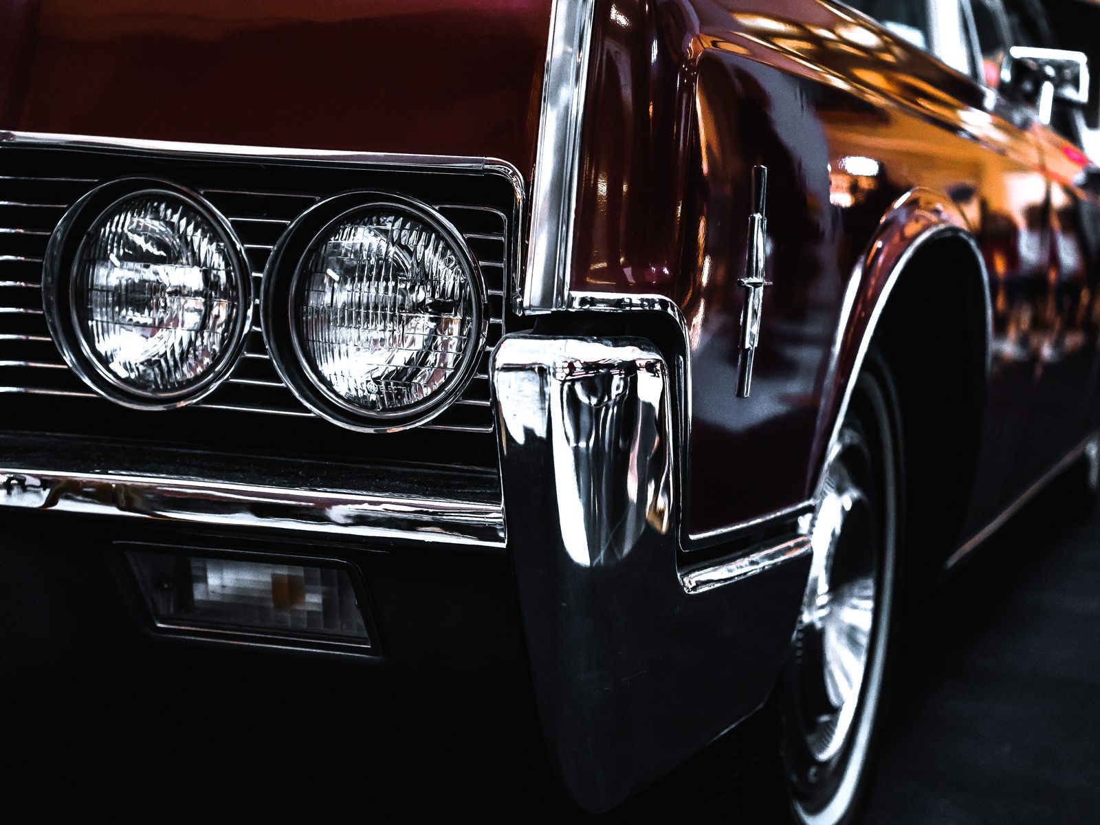 The polished chrome and deep maroon paint of a classic saloon under showroom light