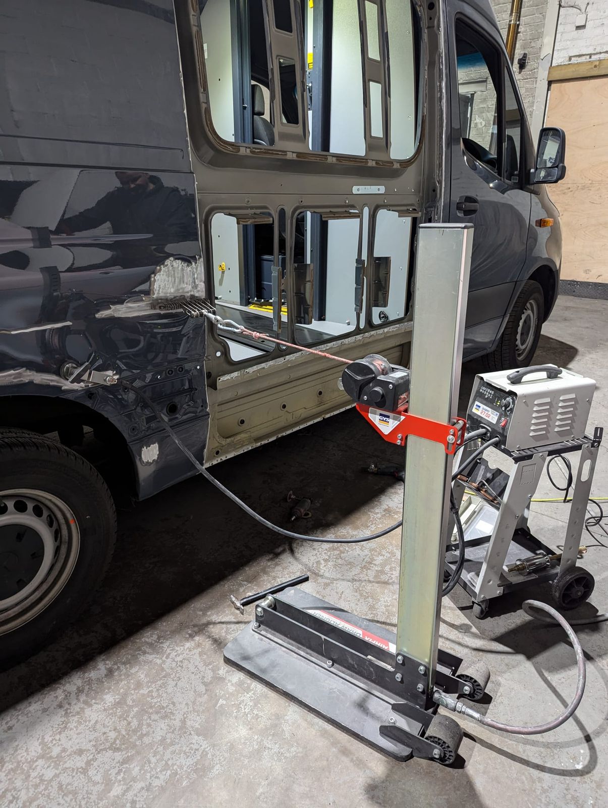 A pull rig and measuring gear set against a van door during accident repair at Rewind