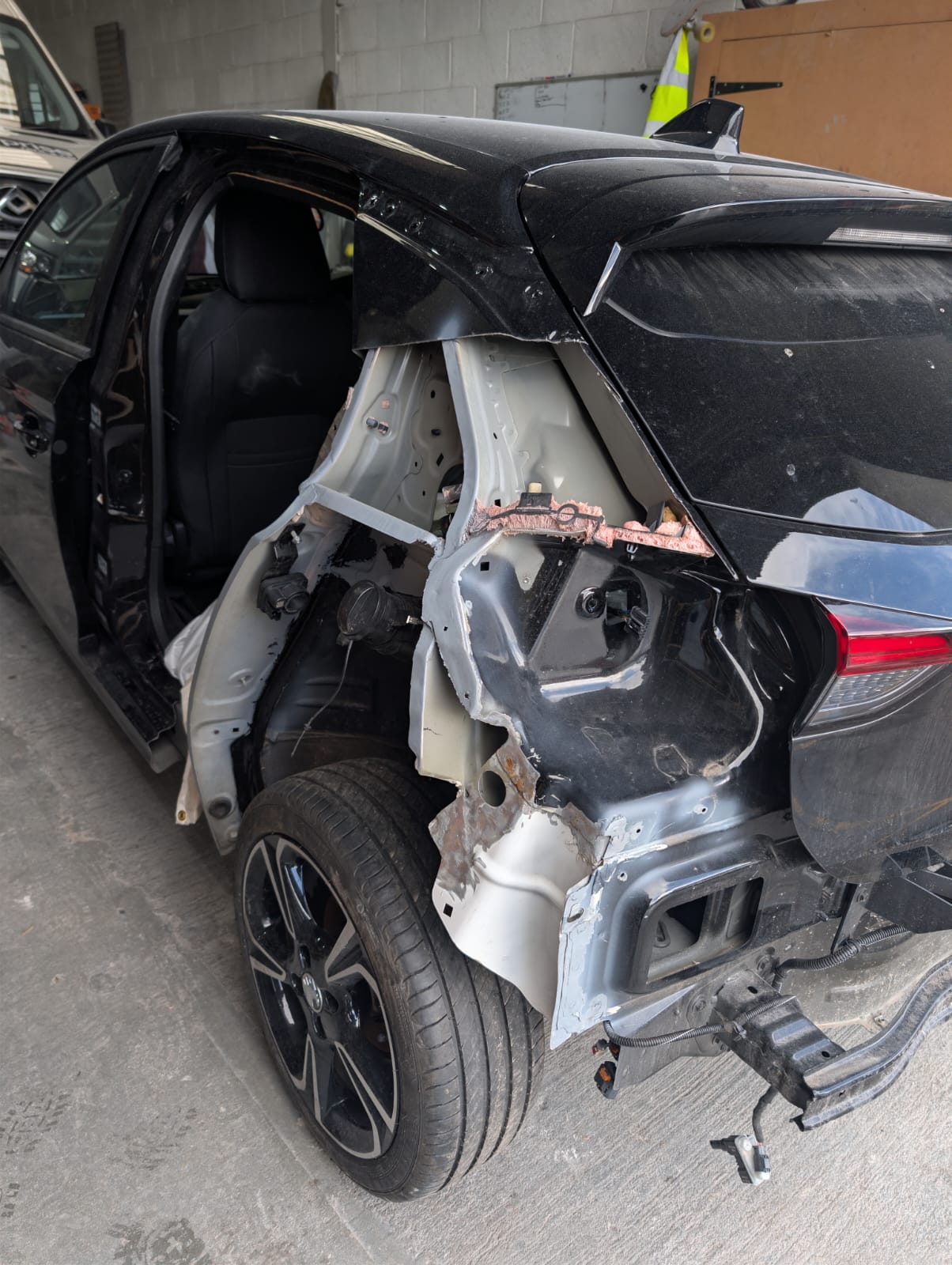 A black hatchback with the rear quarter panel cut away mid structural repair
