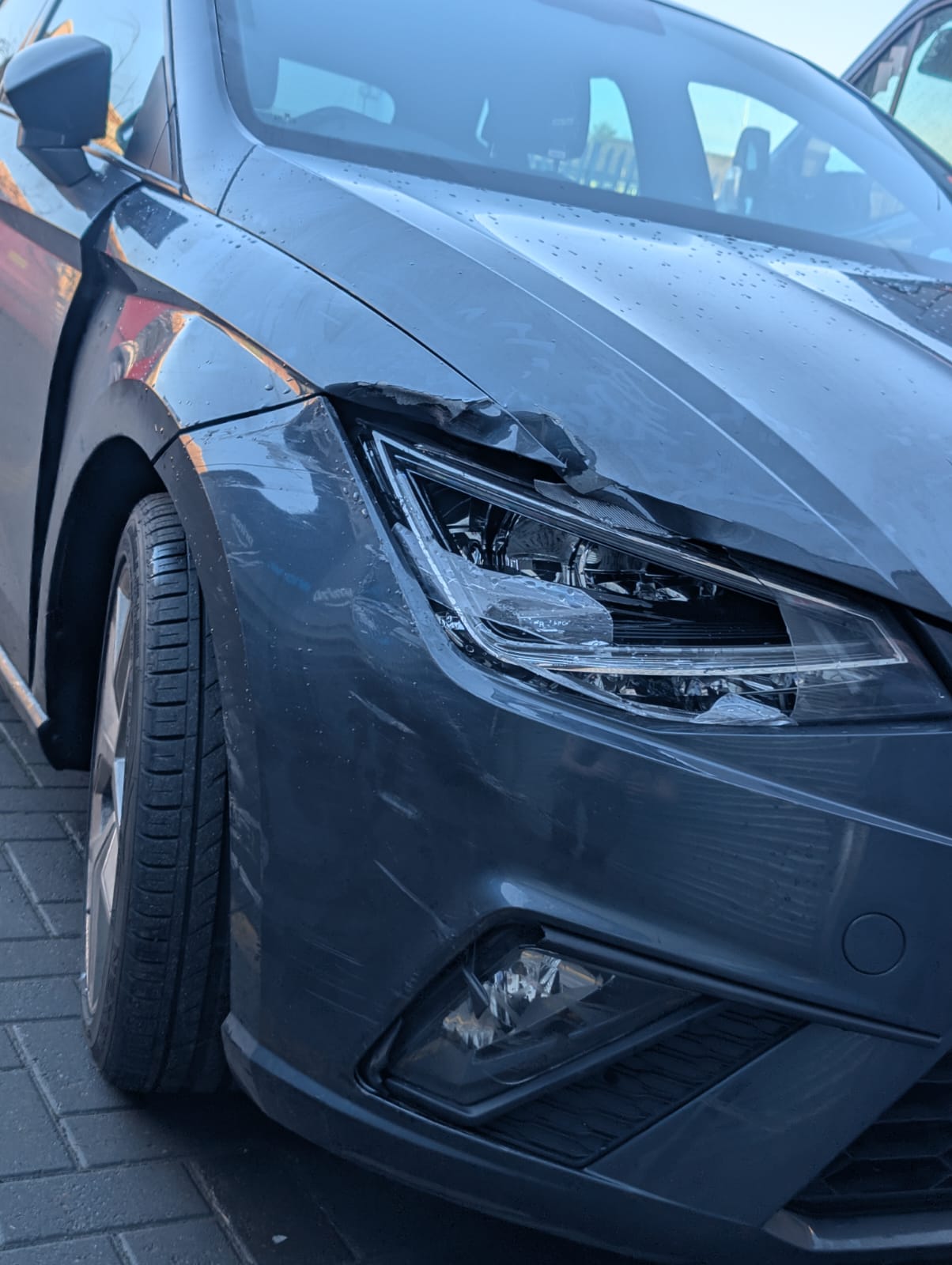 A cracked headlamp and bonnet edge on a grey SEAT after a front-end knock