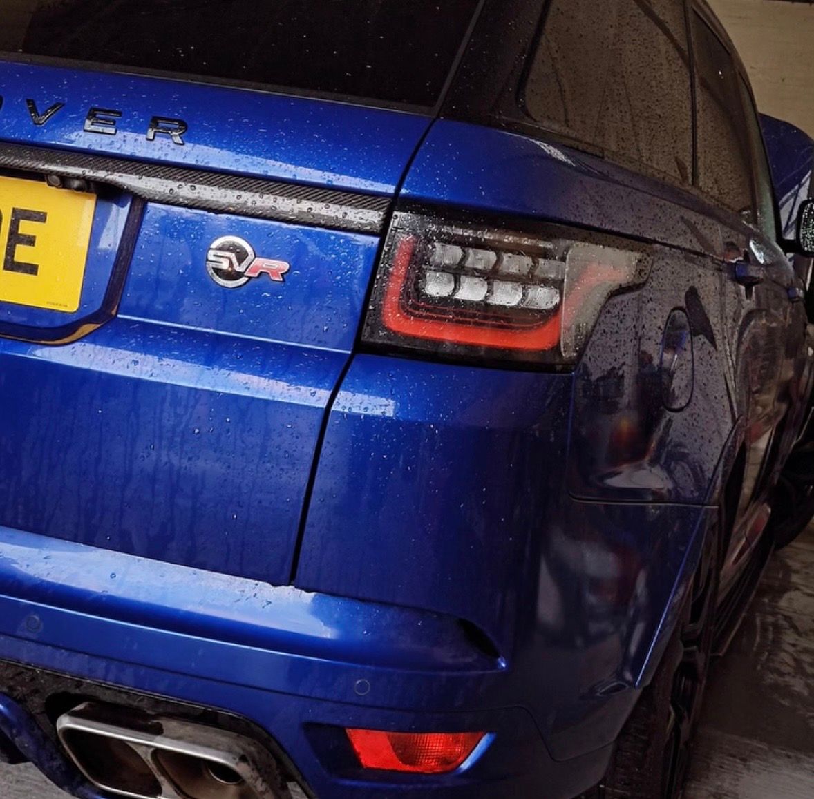 The rear of a blue Range Rover Sport SVR under workshop lighting