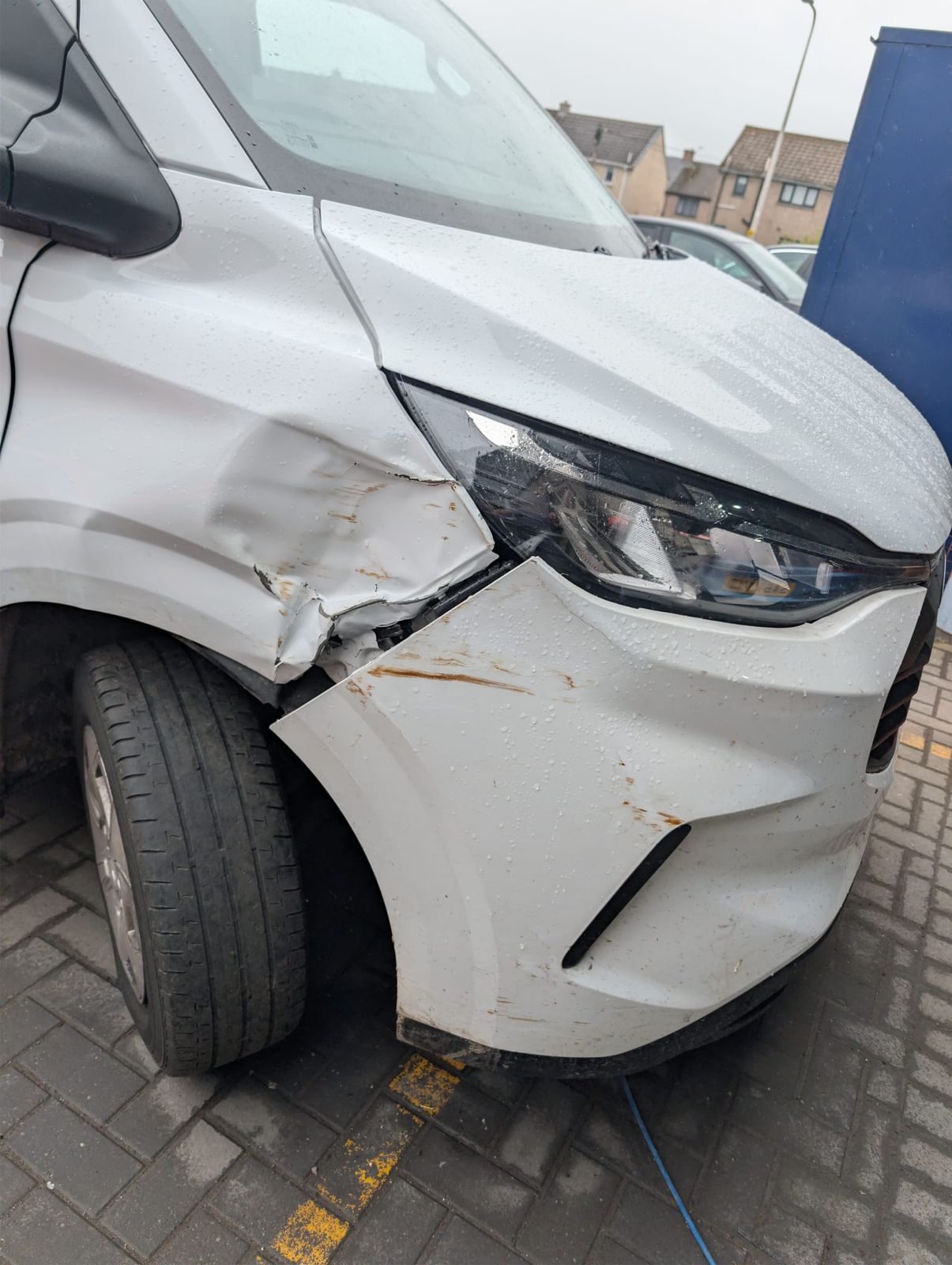 A white van with a dented front wing and scuffed bumper after a collision